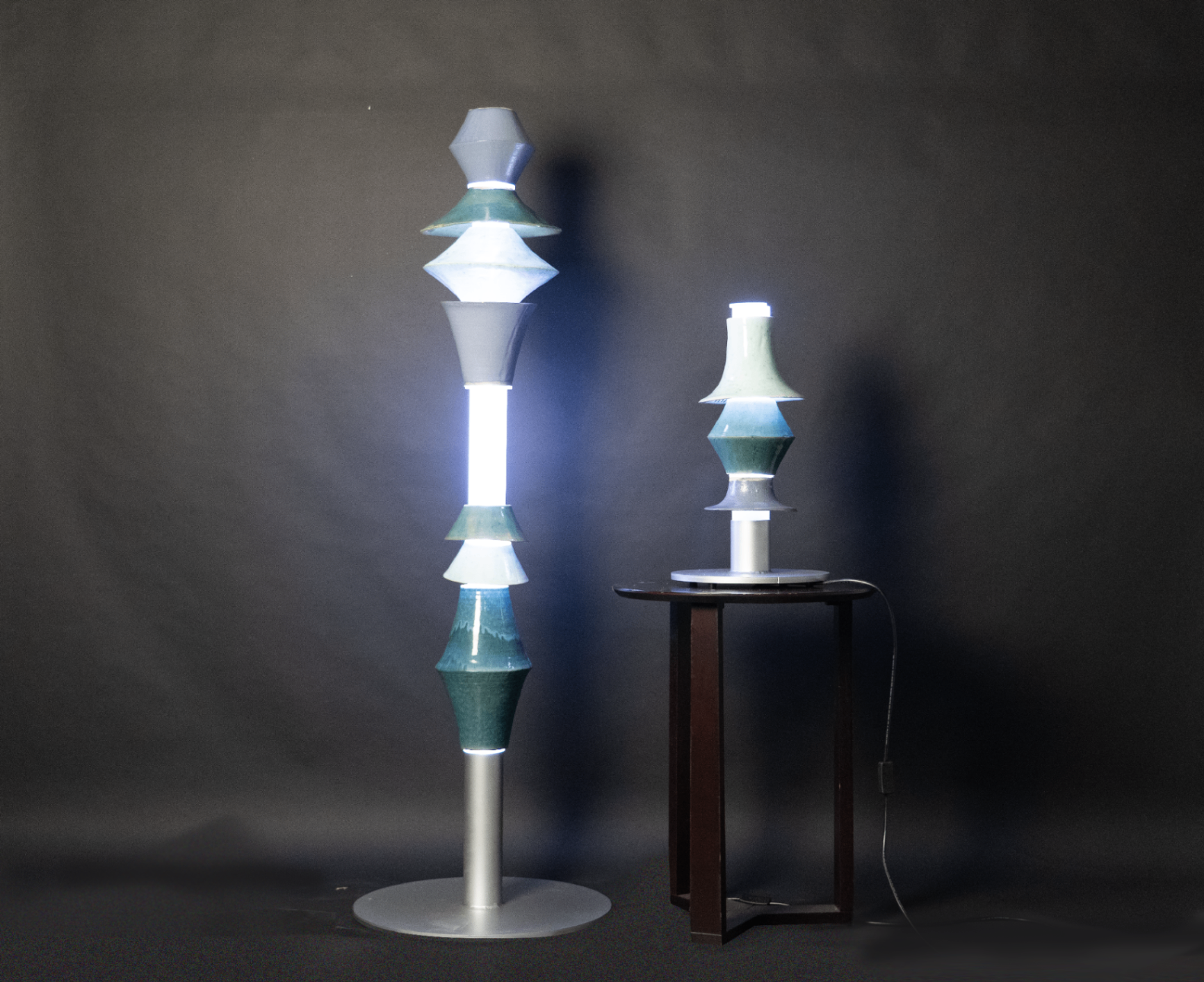 thi modular ceramic lighting illuminated at night — floor and table lamps glowing